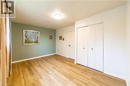Room featuring wood-finish flooring, a sage green accent wall, and a white six-panel closet door - 227 Fergus Avenue, Kitchener, ON 