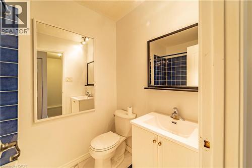 Bathroom featuring a vanity with integrated sink, chrome-finish faucet, rectangular framed wall mirror, and blue tiled wall accents - 227 Fergus Avenue, Kitchener, ON 