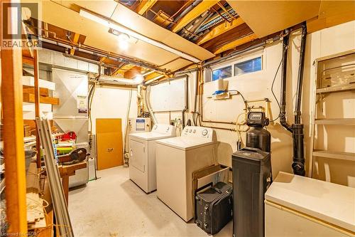 Utility area featuring a water softener system, horizontal slider window, exposed ceiling joists, and concrete flooring - 227 Fergus Avenue, Kitchener, ON 