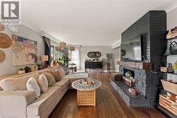 Expansive living area featuring wood-finish flooring, a painted brick fireplace, a wood mantle, and built-in shelving - 
