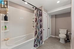 White bathtub with integrated shelving, tiled flooring, and a white toilet - 
