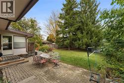 Expansive backyard featuring a paver patio, manicured lawn, mature trees, and exterior siding - 