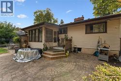 Expansive paver patio with a circular pattern, leading to a three-step wood-finish deck - 