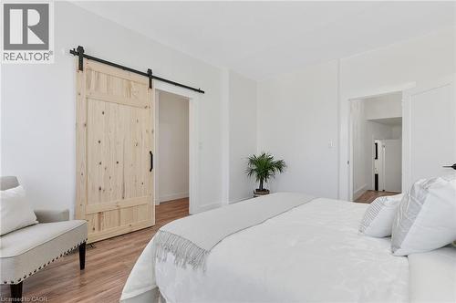 Wood-finish flooring throughout, white walls, and a natural wood barn door with black hardware - 164 Wilson Street, Hamilton, ON 