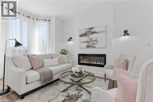 Contemporary fireplace with shiplap-accented surround, hardwood-style flooring, and a bay window - 164 Wilson Street, Hamilton, ON 