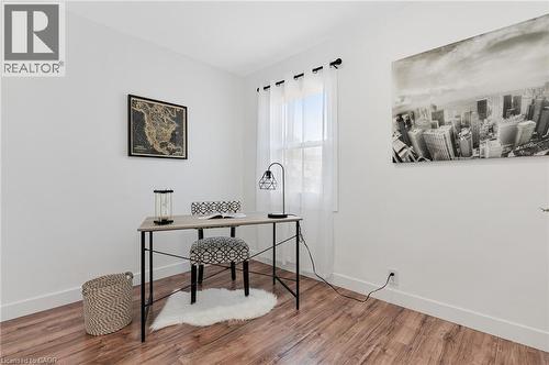 Dedicated workspace featuring a wood-finish desk with metal frame and cross-bracing, paired with upholstered seating - 164 Wilson Street, Hamilton, ON 