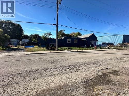 Single-story exterior featuring blue siding, a peaked roofline, and perimeter chain-link fencing - 150 Princess Street, Hamilton, ON 
