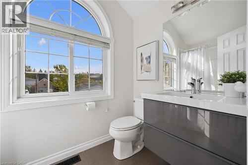 Arch-top window with grid pattern, a modern vanity with a white countertop, a rectangular undermount sink, and a chrome-finish faucet - 6 Branwood Place, Kitchener, ON 