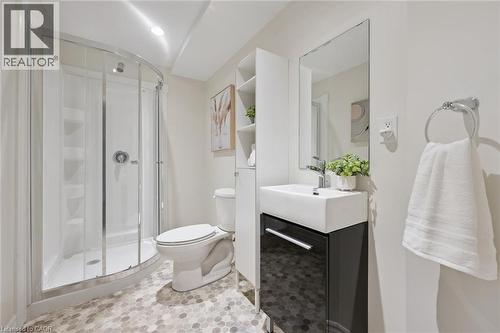 Curved glass shower enclosure, contemporary white toilet, vanity with integrated white sink, wall-mounted mirror, and hexagonal flooring - 6 Branwood Place, Kitchener, ON 