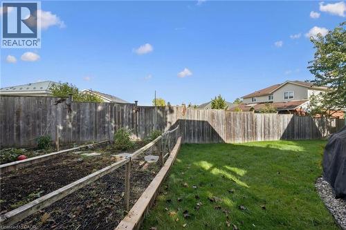 Expansive backyard featuring a manicured lawn, established garden beds, and a wood privacy fence - 6 Branwood Place, Kitchener, ON 