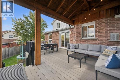 Expansive covered deck with composite decking, exposed wood beam ceiling, brick exterior, and sliding glass door access - 6 Branwood Place, Kitchener, ON 