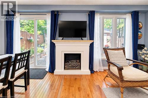 Hardwood flooring, a white mantelpiece with a wood-finish top, a fireplace insert, a sliding glass door, and a window - 327 Oprington Place, Kitchener, ON 