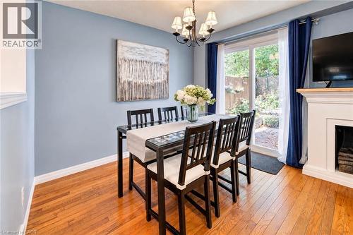 Wood-finish flooring, sliding glass patio door, built-in fireplace, and a chandelier fixture - 327 Oprington Place, Kitchener, ON 