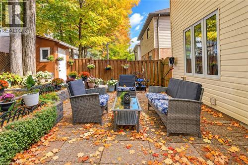 Paved patio area, raised garden beds with stone retainers, wood privacy fencing, a storage shed, and a siding exterior - 327 Oprington Place, Kitchener, ON 