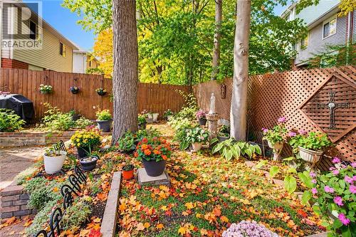 Fenced backyard featuring mature trees, a wooden privacy fence, and a decorative lattice panel - 327 Oprington Place, Kitchener, ON 
