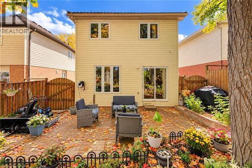 Rear exterior featuring light-colored siding, a paved patio, and a sliding glass door - 327 Oprington Place, Kitchener, ON 