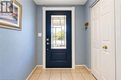 Entryway featuring a navy front door with decorative glass, tile flooring, and white bi-fold closet doors - 327 Oprington Place, Kitchener, ON 