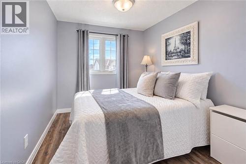 Wood-finish flooring, light blue wall paint, and a double-pane window with white trim - 327 Oprington Place, Kitchener, ON 