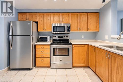 Kitchen featuring wood cabinetry, light-toned countertops, stainless steel appliances, and tiled flooring - 327 Oprington Place, Kitchener, ON 