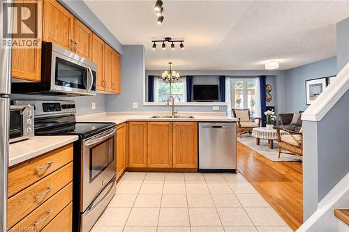 Kitchen featuring wood-finish cabinetry, stainless steel appliances, and tile flooring - 327 Oprington Place, Kitchener, ON 