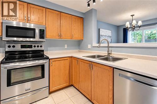 Kitchen featuring wood cabinetry, stainless steel appliances, a double basin sink, and track lighting - 327 Oprington Place, Kitchener, ON 