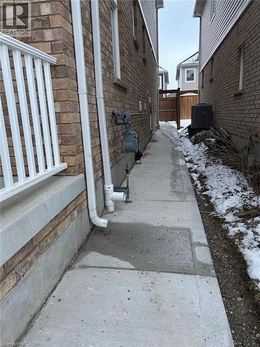Brick veneer exterior featuring a poured concrete side walkway, white metal railing, and wood-paneled privacy fencing - 31 Sofitel Drive, Kitchener, ON 