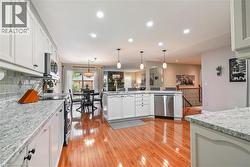 Kitchen featuring white cabinetry, stone-patterned countertops, wood-finish flooring, recessed lighting, and stainless steel dishwasher - 