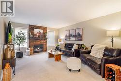 Living area featuring a floor-to-ceiling textured stone fireplace surround, a dark wood mantel, and windows with horizontal blinds - 