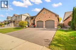 Brick exterior facade with stone-detailed gables, two-car garage with arched entryways, and paved driveway - 