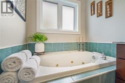 Built-in jetted soaking tub featuring a ceramic tile surround, integrated chrome faucet hardware, and a double-hung window - 