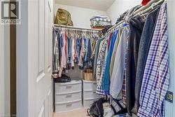 Walk-in closet featuring L-shaped built-in wire shelving and hanging rods - 