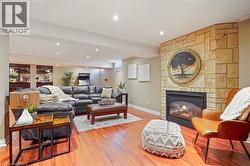 Living area featuring wood-finish flooring, recessed lighting, and a floor-to-ceiling stone-veneer fireplace with a glass-front insert - 