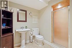Bathroom featuring a pedestal sink with chrome faucet, walk-in shower with frame, tile flooring, and wall-mounted vanity mirror - 