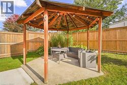 Hexagonal wooden gazebo featuring an exposed beam ceiling, concrete foundation, and perimeter wood privacy fencing - 