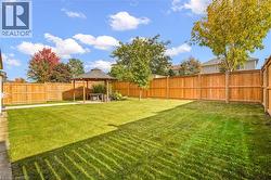 Expansive backyard featuring a manicured lawn, full-height wood fencing, and a permanent gazebo structure - 