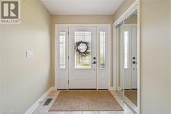 Entryway featuring a white door with decorative glass inlay, dual sidelights, ceramic tile flooring, and a floor-to-ceiling mirrored sliding closet door - 