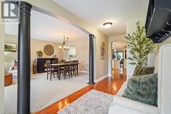 Interior space featuring decorative dark architectural columns, wood-finish flooring, and a multi-arm pendant light fixture - 