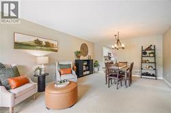 Open-concept interior featuring neutral wall tones, neutral carpeting, and a rustic-style chandelier - 