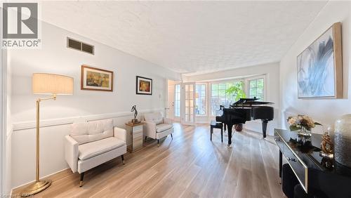 Light-filled space featuring wood-finish flooring, wainscoting, and a multi-pane bay window with French doors - 488 Heather Hill Place, Waterloo, ON 