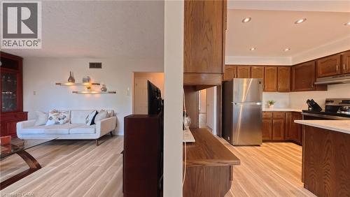 Kitchen featuring wood cabinetry, stainless steel appliances, and wood-finish flooring throughout - 488 Heather Hill Place, Waterloo, ON 