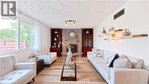 Living area featuring wood-finish flooring, a floor-to-ceiling brick fireplace, and dual built-in dark wood cabinetry - 488 Heather Hill Place, Waterloo, ON 