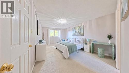 Neutral-toned bedroom featuring carpeting, a multi-panel door with gold-tone hardware, and a center-mounted light fixture - 488 Heather Hill Place, Waterloo, ON 