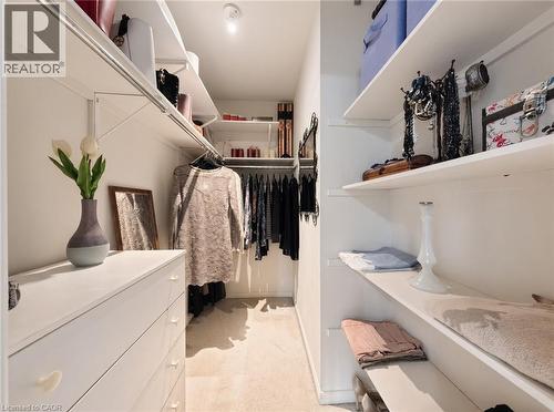 Walk-in storage space featuring custom white shelving, hanging rods, and integrated cabinetry - 488 Heather Hill Place, Waterloo, ON 