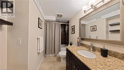 Bathroom featuring a stone-top vanity with dark wood-finish cabinetry, an oval undermount sink, a framed vanity mirror, and built-in wall shelving - 488 Heather Hill Place, Waterloo, ON 