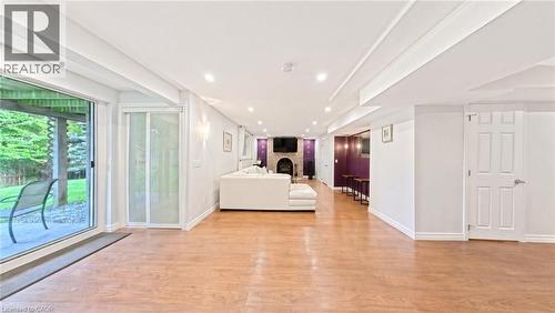 Spacious room featuring wood-finish flooring, recessed lighting, and a stone-surround fireplace - 488 Heather Hill Place, Waterloo, ON 