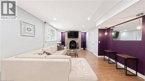 Living space featuring wood-finish flooring, recessed lighting, a stone-surround fireplace with a hearth, and a large wall-mounted mirror - 488 Heather Hill Place, Waterloo, ON 