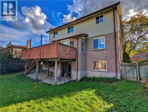Multi-level exterior featuring light brick and horizontal siding, an elevated wood deck, a ground-level concrete patio, and a fenced backyard - 488 Heather Hill Place, Waterloo, ON 