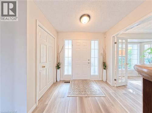 Entryway featuring a six-panel front door with sidelights, wood-finish flooring, double-door coat closet, and French doors - 488 Heather Hill Place, Waterloo, ON 