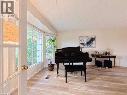 Light-filled room featuring wood-finish flooring, large bay windows, and French doors with brass-finish hardware - 488 Heather Hill Place, Waterloo, ON 