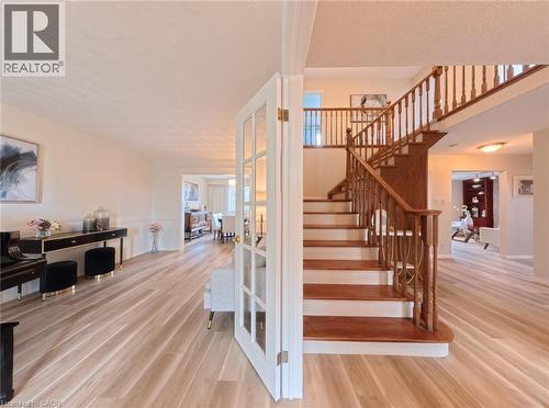 Staircase featuring a wood railing and balusters, light-toned wood-finish flooring, and glass-paned French doors - 488 Heather Hill Place, Waterloo, ON 